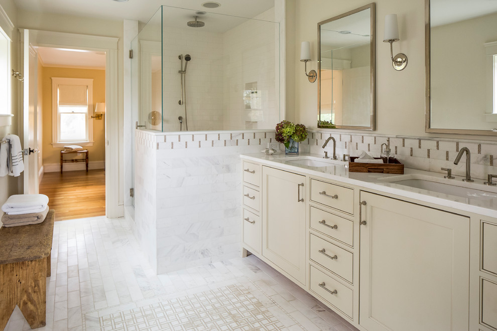 This is an example of a large transitional master bathroom in Providence with flat-panel cabinets, beige cabinets, a corner shower, white tile, mosaic tile, beige walls, marble floors, an undermount sink and marble benchtops.