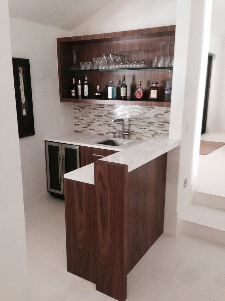 Inspiration for a small transitional l-shaped home bar in Miami with an undermount sink, ceramic floors, multi-coloured splashback, stone tile splashback, dark wood cabinets, quartz benchtops and flat-panel cabinets.
