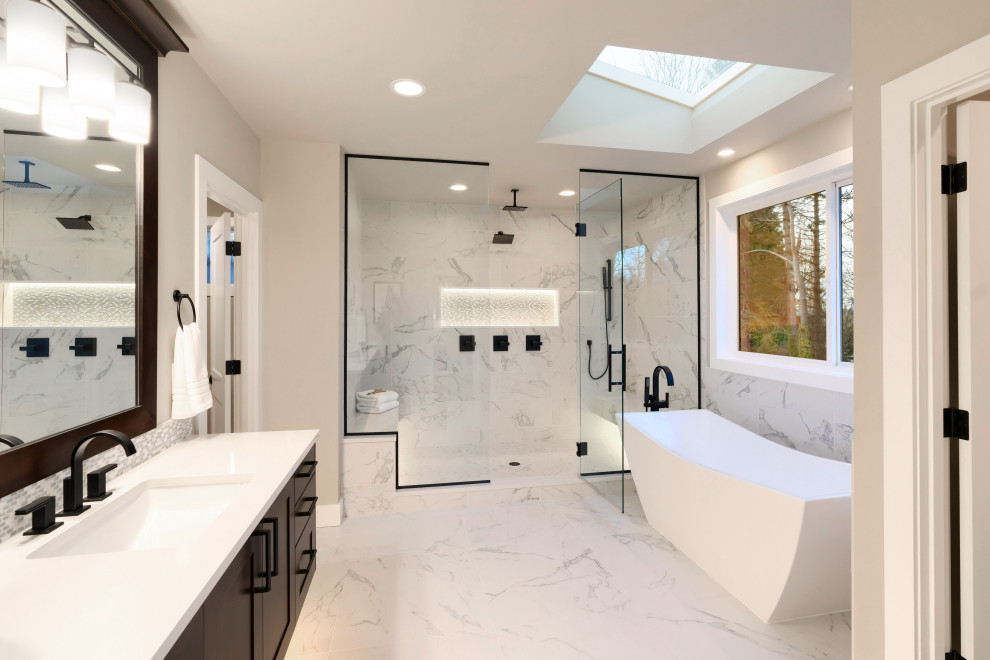 Bild på ett stort vit vitt en-suite badrum, med skåp i shakerstil, bruna skåp, ett fristående badkar, vit kakel, porslinskakel, vita väggar, klinkergolv i porslin, ett undermonterad handfat, bänkskiva i kvartsit, vitt golv och dusch med gångjärnsdörr