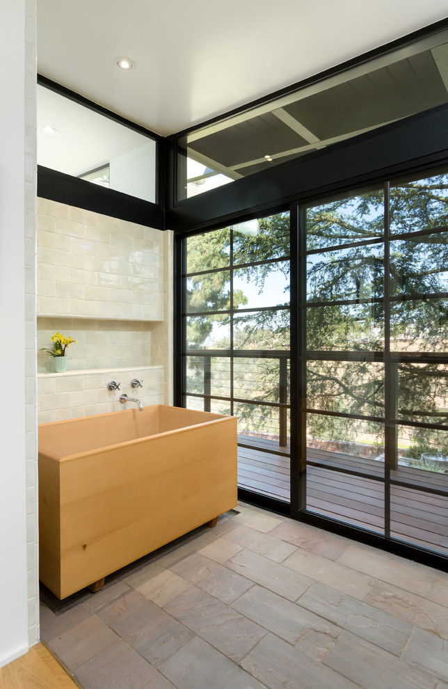 Photo of a large midcentury master bathroom in Los Angeles with shaker cabinets, light wood cabinets, a japanese tub, an alcove shower, a wall-mount toilet, white tile, ceramic tile, white walls, slate floors, an undermount sink, soapstone benchtops, brown floor and a hinged shower door.