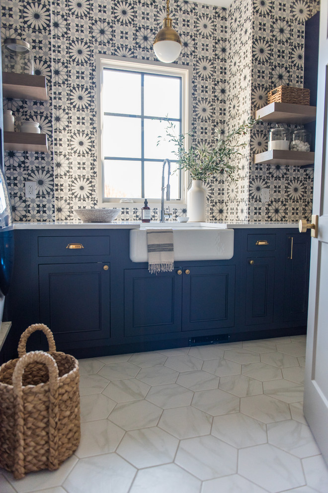 Design ideas for a large transitional dedicated laundry room in Indianapolis with a farmhouse sink, recessed-panel cabinets, blue cabinets, quartzite benchtops, white walls, ceramic floors, a side-by-side washer and dryer and white floor.