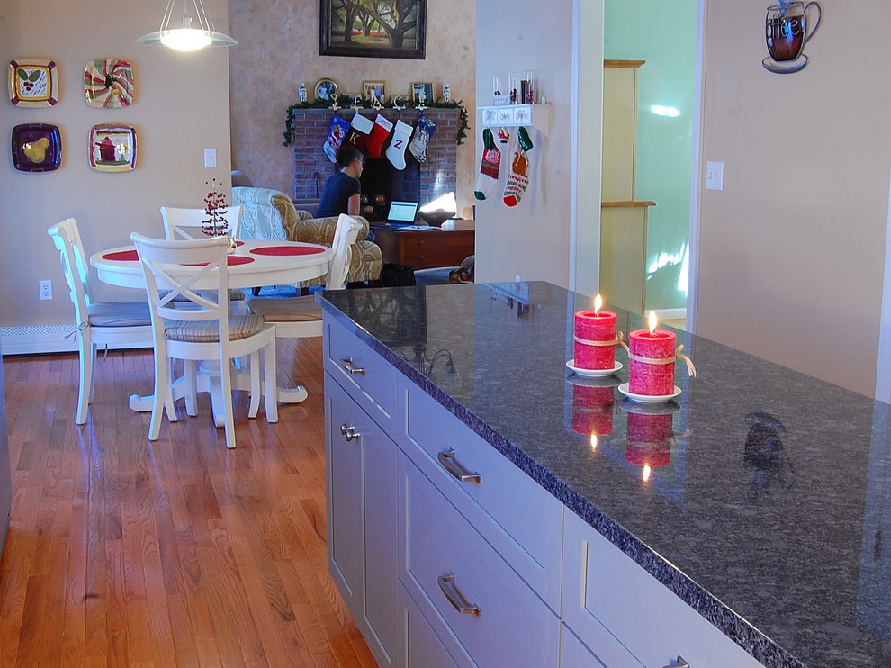 Mid-sized transitional l-shaped medium tone wood floor eat-in kitchen photo in Boston with a farmhouse sink, shaker cabinets, white cabinets, quartz countertops, white backsplash, subway tile backsplash, stainless steel appliances and an island