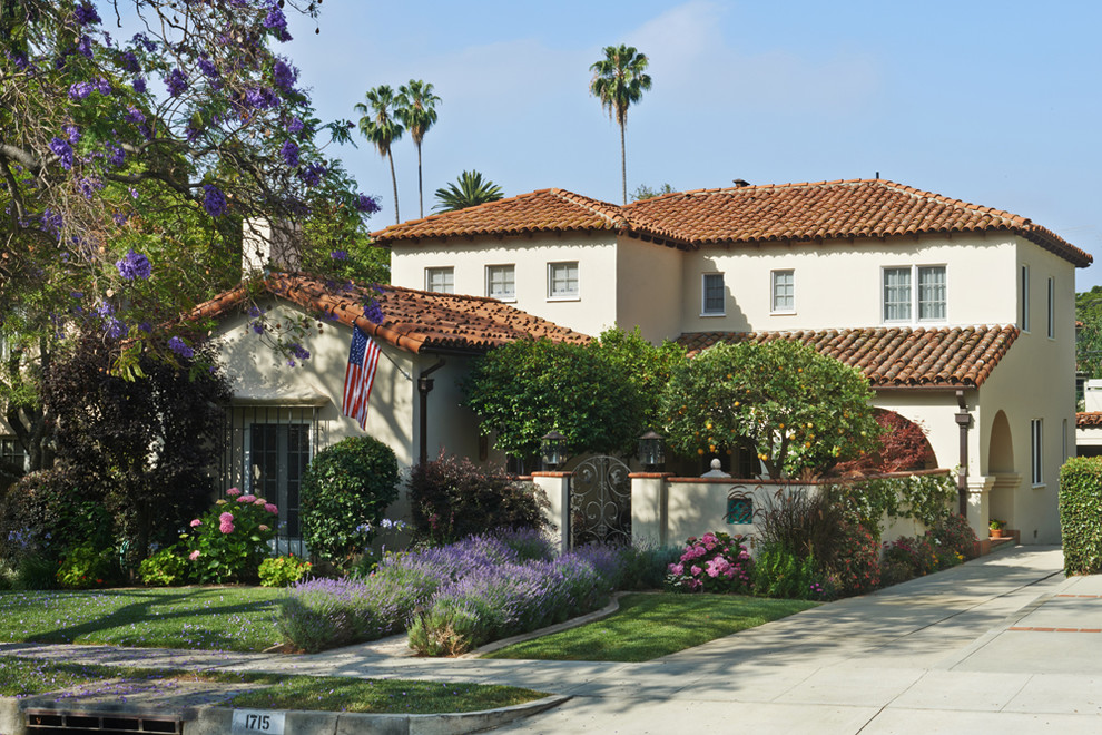 Inspiration for a mid-sized mediterranean two-storey stucco beige exterior in Los Angeles with a clipped gable roof.