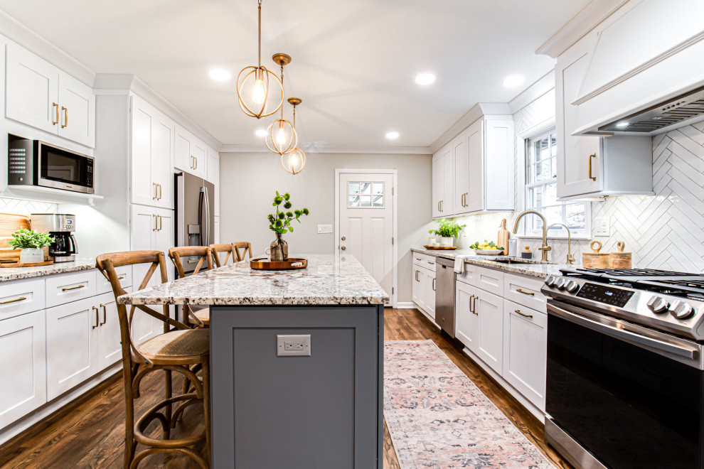 Bild på ett mellanstort vintage flerfärgad flerfärgat kök, med en undermonterad diskho, skåp i shakerstil, vita skåp, granitbänkskiva, vitt stänkskydd, stänkskydd i tunnelbanekakel, rostfria vitvaror, mellanmörkt trägolv, en köksö och brunt golv