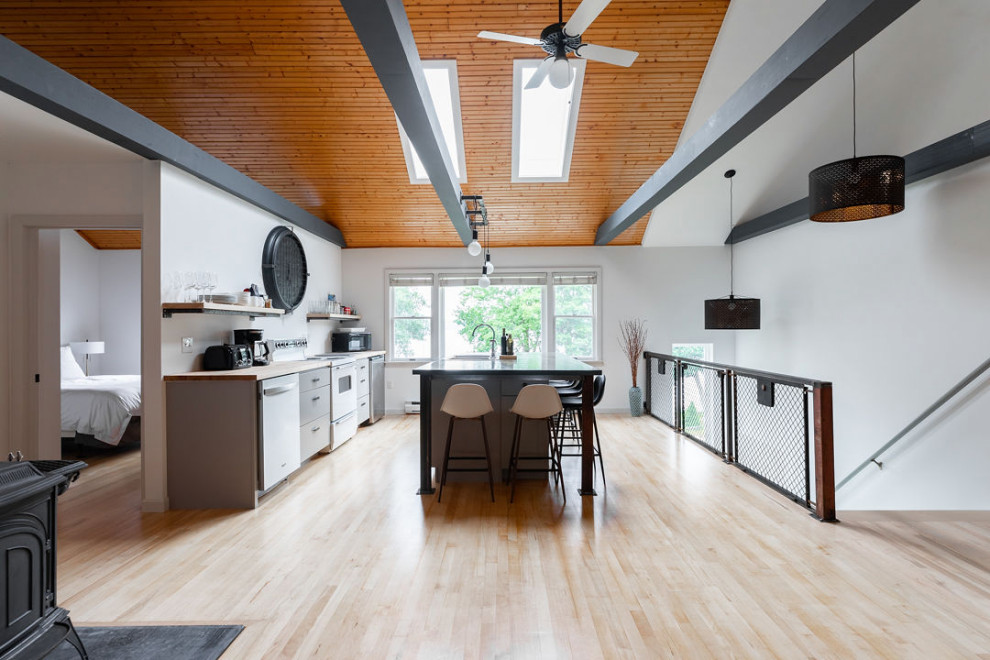 Inspiration for a mid-sized industrial single-wall light wood floor and exposed beam open concept kitchen remodel in Portland Maine with a double-bowl sink, flat-panel cabinets, gray cabinets, concrete countertops, stainless steel appliances, an island and gray countertops