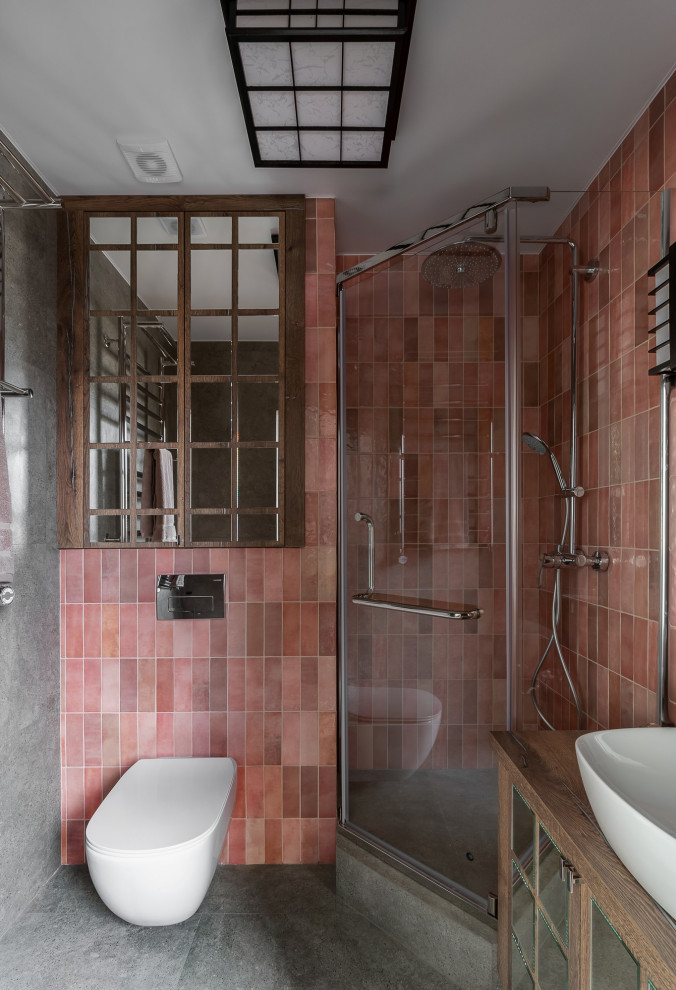 На фото: главная ванная комната среднего размера в восточном стиле с стеклянными фасадами, темными деревянными фасадами, угловым душем, инсталляцией, розовой плиткой, керамической плиткой, розовыми стенами, полом из керамогранита, накладной раковиной, столешницей из ламината, серым полом, душем с распашными дверями, коричневой столешницей, зеркалом с подсветкой, тумбой под одну раковину, напольной тумбой, балками на потолке и панелями на части стены с