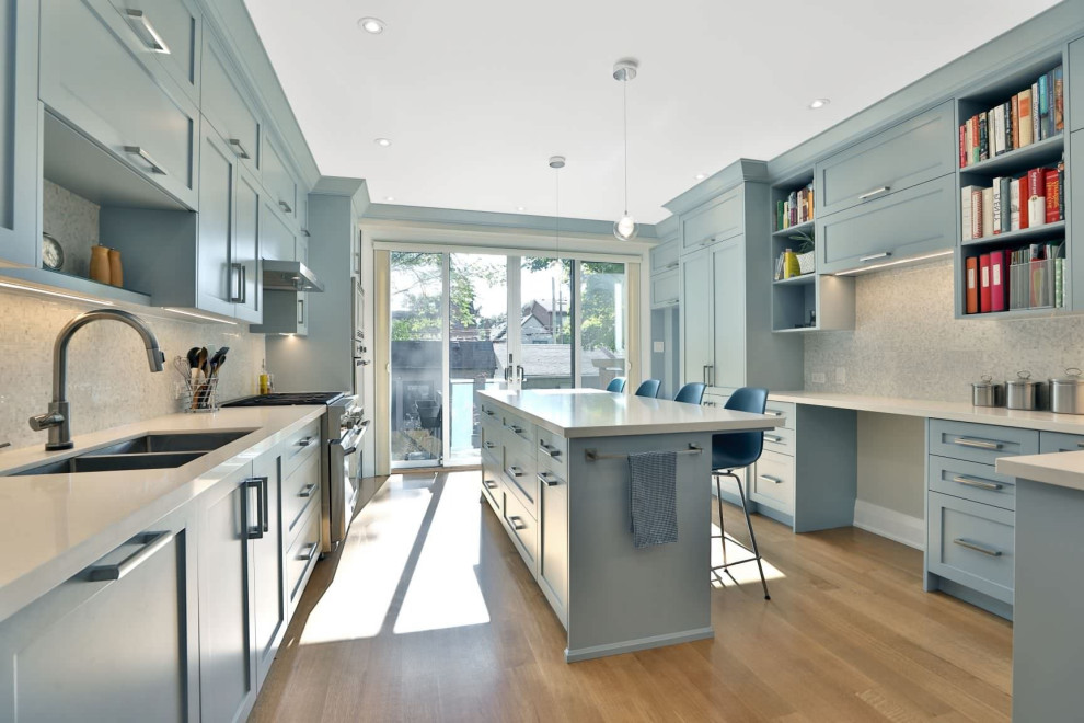 Mid-sized trendy u-shaped medium tone wood floor and yellow floor enclosed kitchen photo in DC Metro with an undermount sink, shaker cabinets, blue cabinets, quartz countertops, white backsplash, mosaic tile backsplash, stainless steel appliances, an island and white countertops