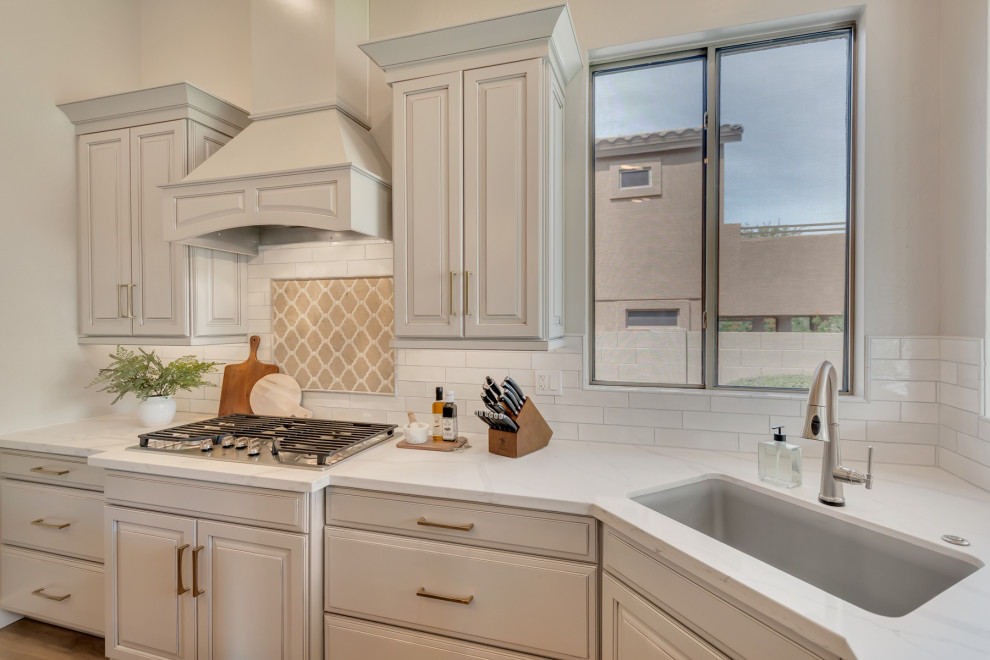 Mid-sized transitional u-shaped eat-in kitchen photo in Phoenix with an undermount sink, raised-panel cabinets, gray cabinets, quartz countertops, white backsplash, subway tile backsplash, stainless steel appliances, an island and white countertops