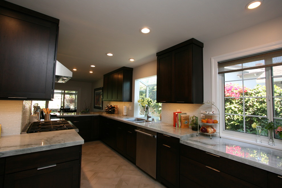 Example of a mid-sized transitional l-shaped porcelain tile kitchen design in Orange County with a double-bowl sink, recessed-panel cabinets, dark wood cabinets, quartzite countertops, white backsplash, glass tile backsplash, stainless steel appliances and no island