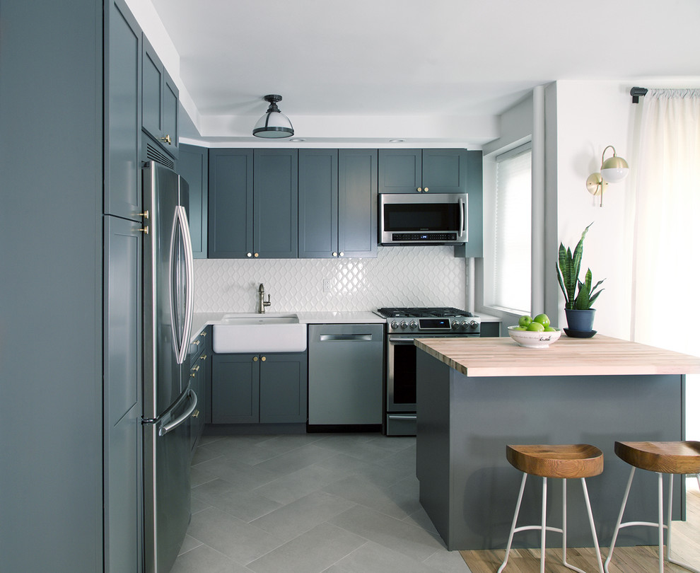 Inspiration for a mid-sized traditional l-shaped eat-in kitchen in New York with a farmhouse sink, raised-panel cabinets, dark wood cabinets, quartz benchtops, white splashback, subway tile splashback, stainless steel appliances, porcelain floors and with island.