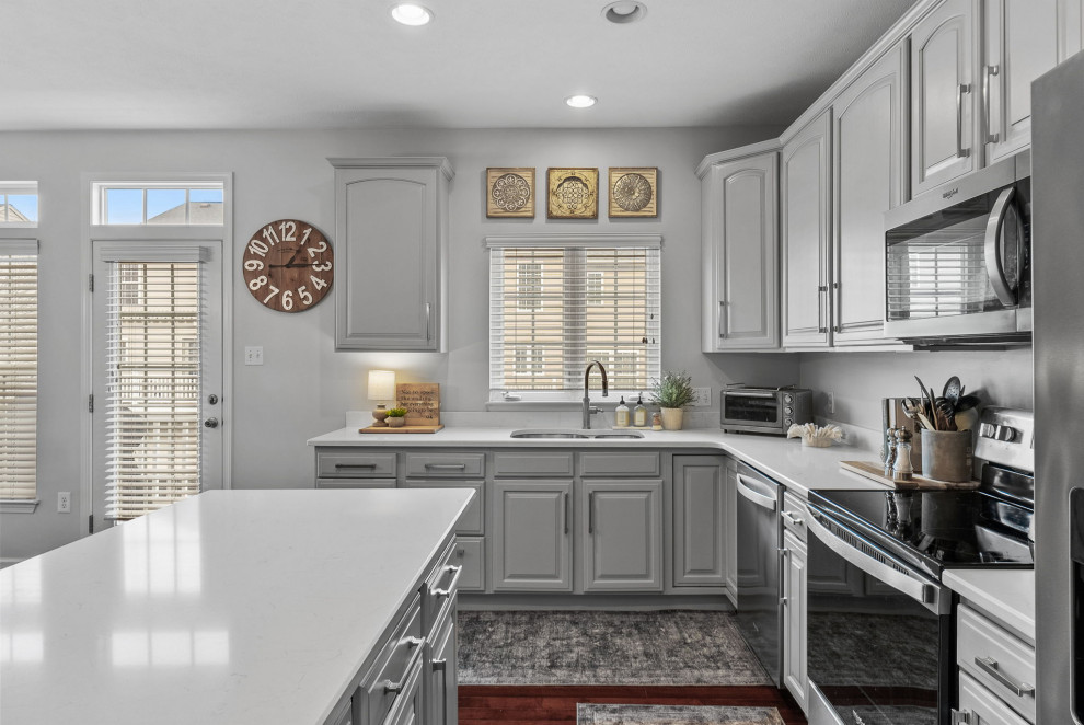 Example of a transitional dark wood floor eat-in kitchen design with a double-bowl sink, gray cabinets, quartz countertops, stainless steel appliances, an island and white countertops