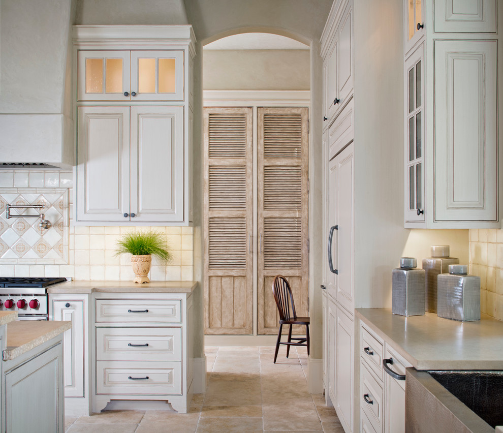 Inspiration for a large transitional l-shaped kitchen pantry in Houston with a drop-in sink, distressed cabinets, limestone benchtops, ceramic splashback, stainless steel appliances, travertine floors, multiple islands and beige splashback.