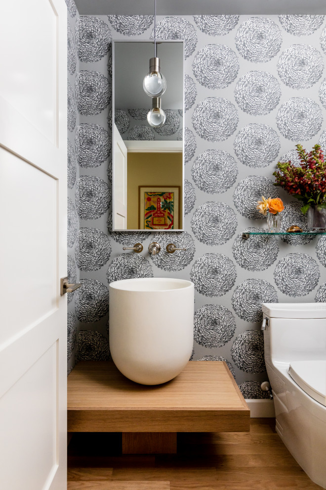 Inspiration for a classic cloakroom with a one-piece toilet, grey walls, medium hardwood flooring, a vessel sink, wooden worktops, brown floors, brown worktops and wallpapered walls.
