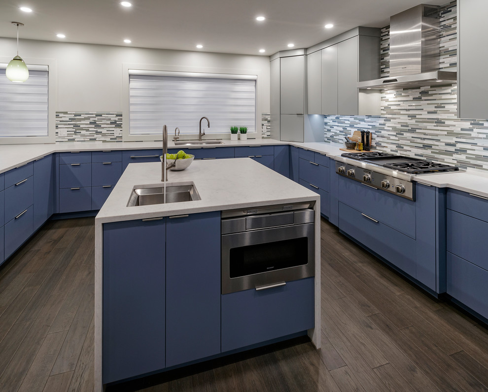 Photo of a large modern u-shaped eat-in kitchen in Calgary with an undermount sink, flat-panel cabinets, blue cabinets, quartzite benchtops, multi-coloured splashback, glass tile splashback, stainless steel appliances, dark hardwood floors, multiple islands, brown floor and white benchtop.