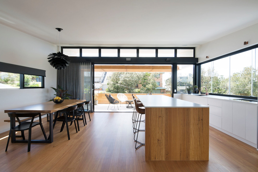 Inspiration for a mid-sized contemporary galley open plan kitchen in Sydney with flat-panel cabinets, white cabinets, quartz benchtops, medium hardwood floors, with island and white benchtop.
