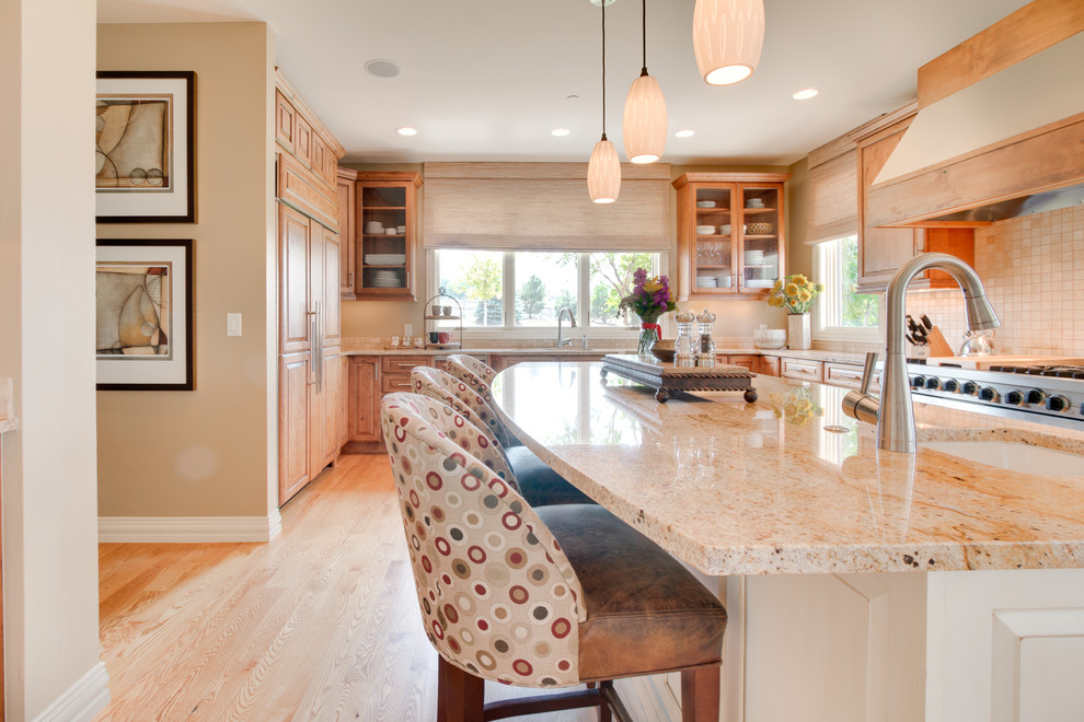 Photo of a large transitional u-shaped open plan kitchen in Denver with a drop-in sink, raised-panel cabinets, light wood cabinets, granite benchtops, beige splashback, glass sheet splashback, stainless steel appliances, light hardwood floors and with island.