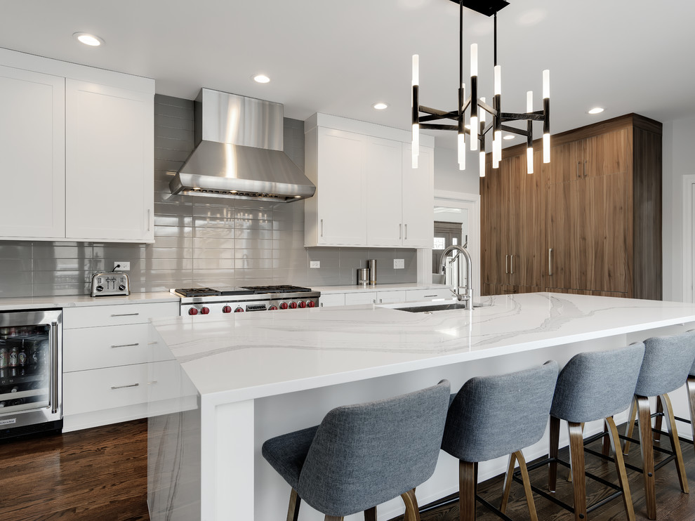 Inspiration for a large modern l-shaped separate kitchen in Chicago with an undermount sink, flat-panel cabinets, white cabinets, quartz benchtops, grey splashback, porcelain splashback, panelled appliances, medium hardwood floors, with island, brown floor and white benchtop.