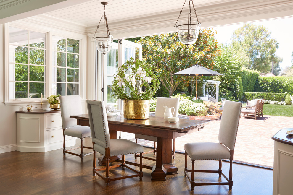 This is an example of a traditional dining room in Orange County with white walls and dark hardwood floors.