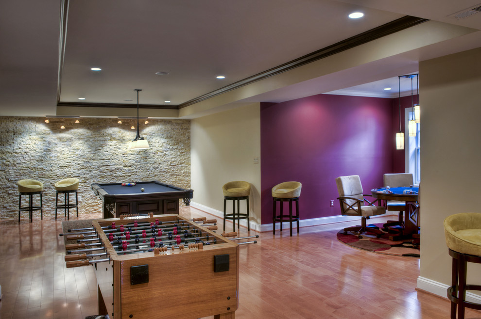 This is an example of a mid-sized contemporary walk-out basement in DC Metro with pink walls and medium hardwood floors.