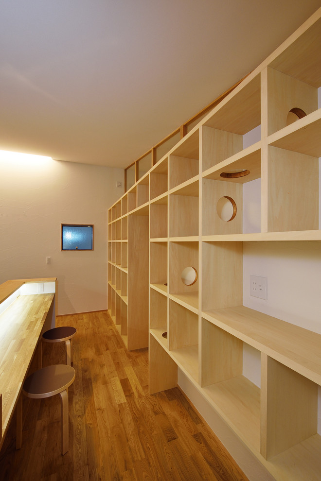 Idéer för att renovera ett stort skandinaviskt hemmabibliotek, med vita väggar, mellanmörkt trägolv, ett inbyggt skrivbord och brunt golv