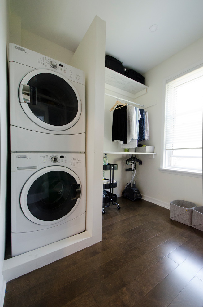 Photo of a mid-sized contemporary utility room in Toronto with white cabinets, laminate benchtops, white walls, dark hardwood floors, a stacked washer and dryer, brown floor and white benchtop.