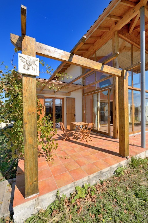 Large contemporary front yard patio in Montpellier with a pergola and tile.