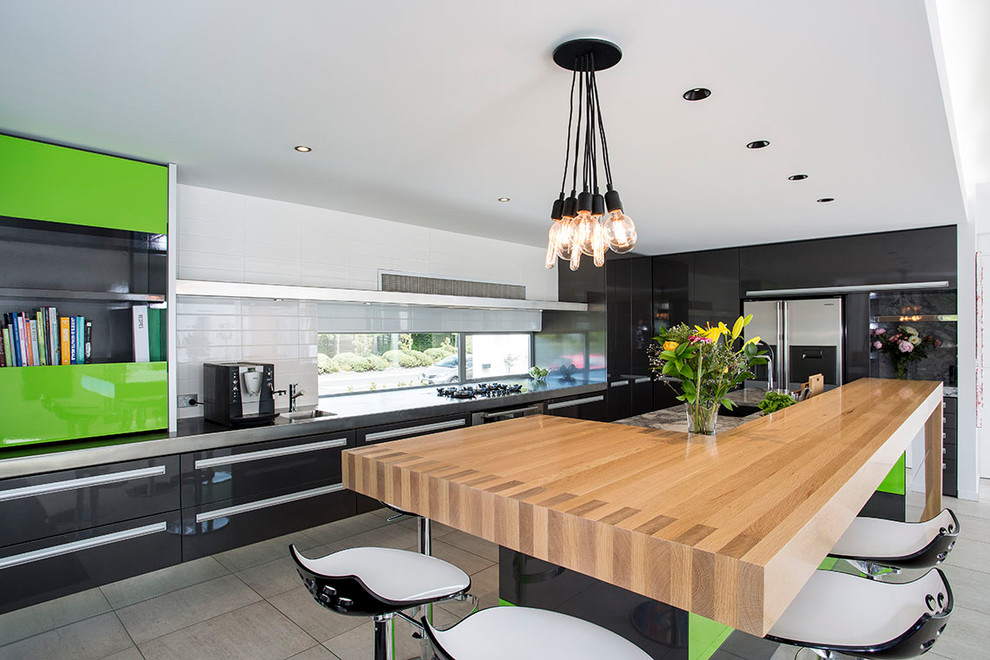 Large contemporary galley eat-in kitchen in Christchurch with an undermount sink, flat-panel cabinets, black cabinets, wood benchtops, stainless steel appliances, ceramic floors, with island and grey floor.