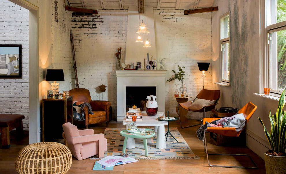 Photo of an eclectic living room in Other with white walls, medium hardwood floors, a standard fireplace, brown floor and brick walls.