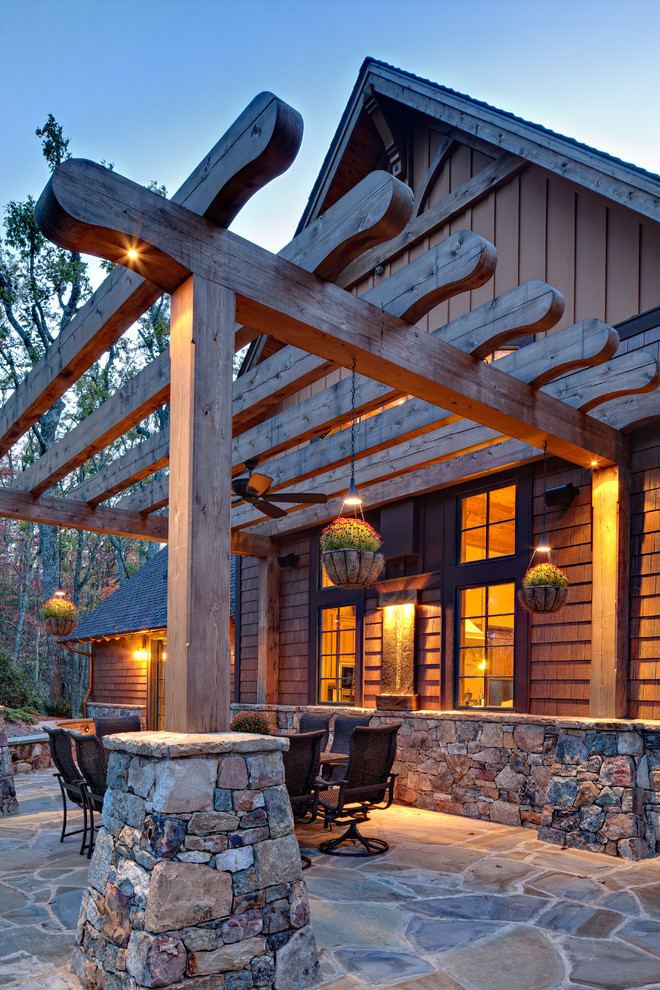 This is an example of a country patio in Other with natural stone pavers and a pergola.