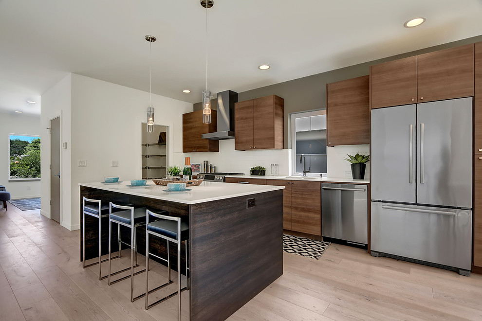 Photo of a contemporary single-wall open plan kitchen in Seattle with flat-panel cabinets, medium wood cabinets, with island, a drop-in sink, quartz benchtops, white splashback and stainless steel appliances.