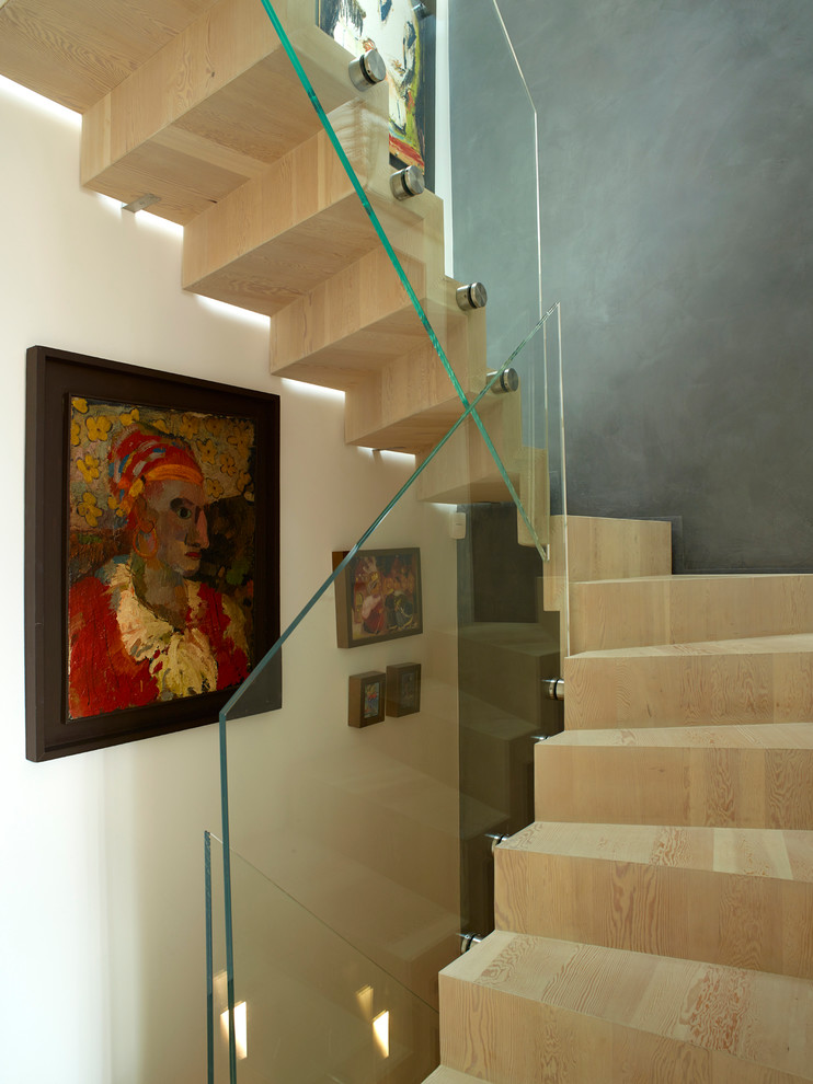 Inspiration for a mid-sized contemporary wood spiral staircase in London with wood risers and glass railing.