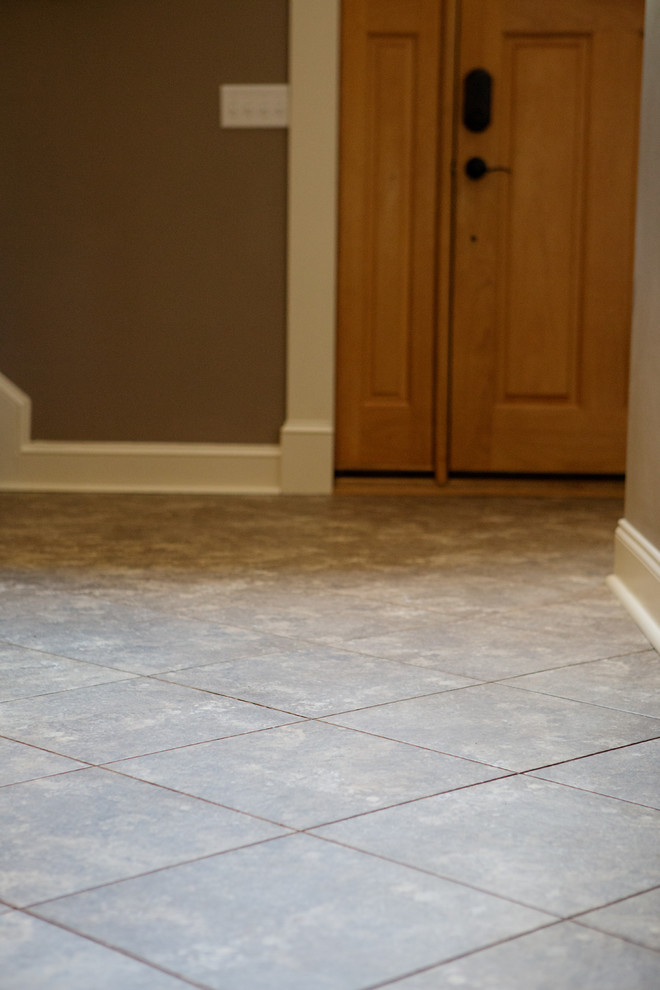 Example of a large transitional vinyl floor single front door design with brown walls and a light wood front door