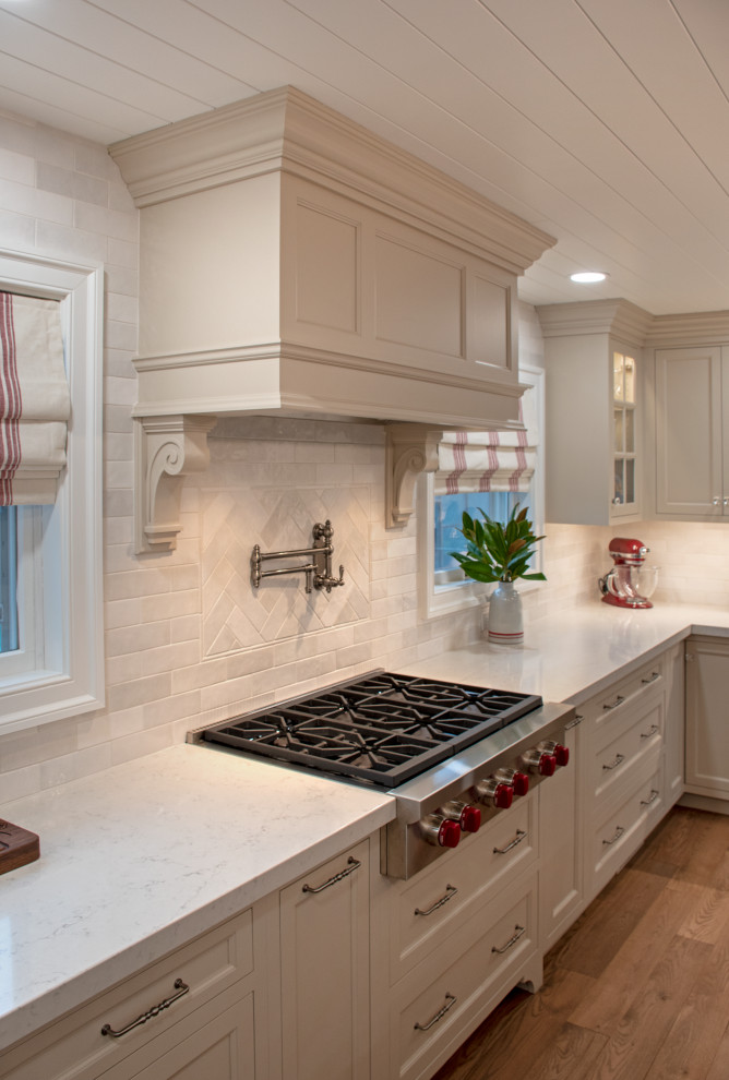 Example of a transitional medium tone wood floor, brown floor and shiplap ceiling eat-in kitchen design with shaker cabinets, beige cabinets, quartz countertops, white backsplash, ceramic backsplash, stainless steel appliances and white countertops
