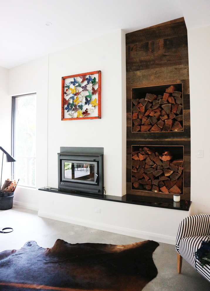 Photo of a mid-sized modern open concept living room in Central Coast with white walls, concrete floors, a standard fireplace, a wood fireplace surround, a wall-mounted tv and grey floor.