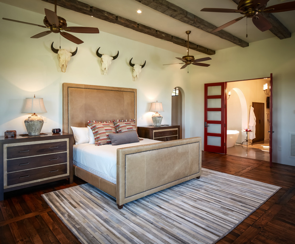 This is an example of a country master bedroom in Houston with white walls, dark hardwood floors and no fireplace.
