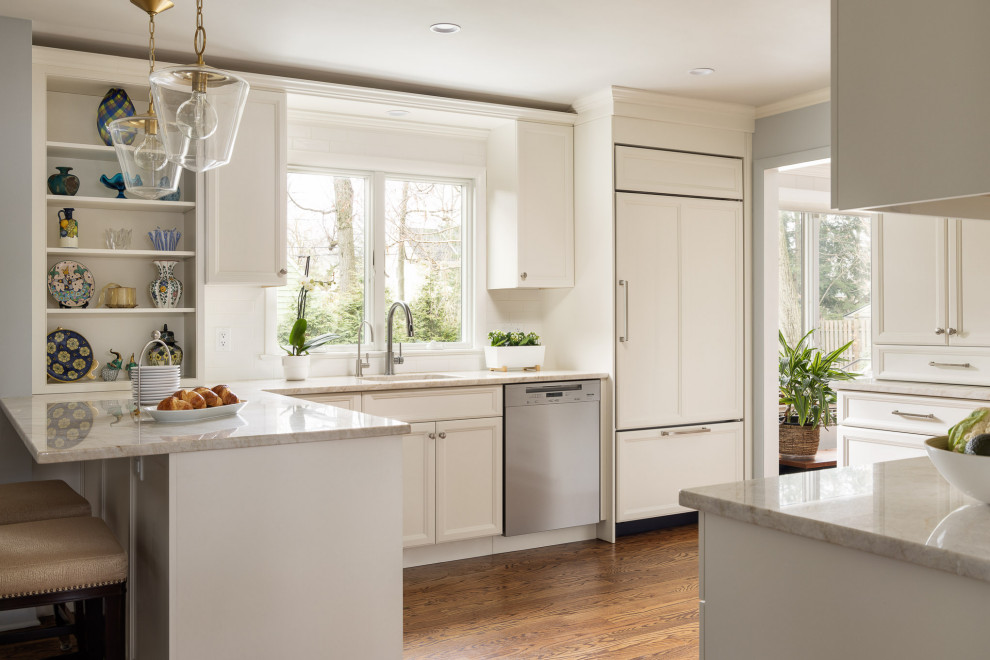 This is an example of a mid-sized transitional l-shaped separate kitchen in New York with an undermount sink, recessed-panel cabinets, beige cabinets, quartzite benchtops, yellow splashback, subway tile splashback, panelled appliances, medium hardwood floors, a peninsula and beige benchtop.