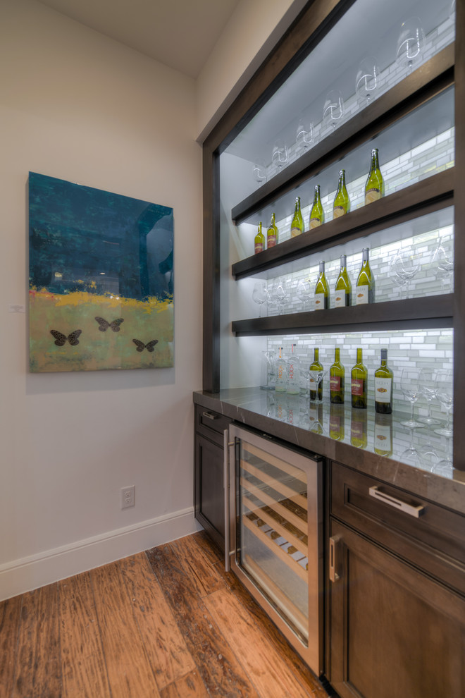 Photo of a small transitional single-wall home bar in Austin with no sink, dark wood cabinets, marble benchtops, multi-coloured splashback, mosaic tile splashback, medium hardwood floors and recessed-panel cabinets.