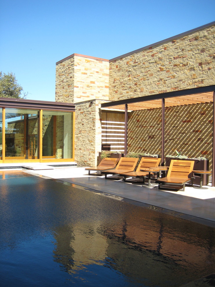 Design ideas for a large contemporary rectangular infinity pool in Austin with tile.
