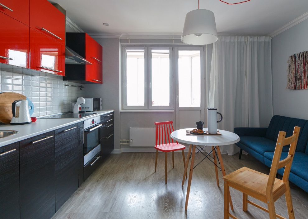 This is an example of a small eclectic single-wall eat-in kitchen in Moscow with flat-panel cabinets, red cabinets, solid surface benchtops, white splashback, ceramic splashback, stainless steel appliances, laminate floors, no island and white benchtop.