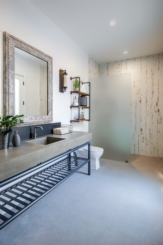 Mid-sized mountain style white tile concrete floor and gray floor walk-in shower photo in Phoenix with a one-piece toilet, white walls, an integrated sink, concrete countertops and gray countertops