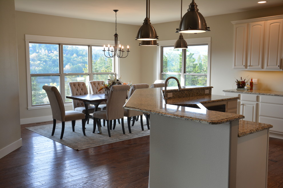 Large transitional l-shaped medium tone wood floor and brown floor kitchen photo with raised-panel cabinets, white cabinets, an island and an undermount sink