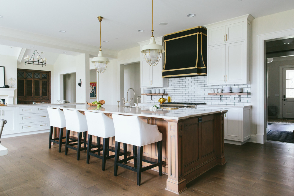 This is an example of a transitional kitchen in Chicago with recessed-panel cabinets, white cabinets, white splashback, subway tile splashback, dark hardwood floors and with island.