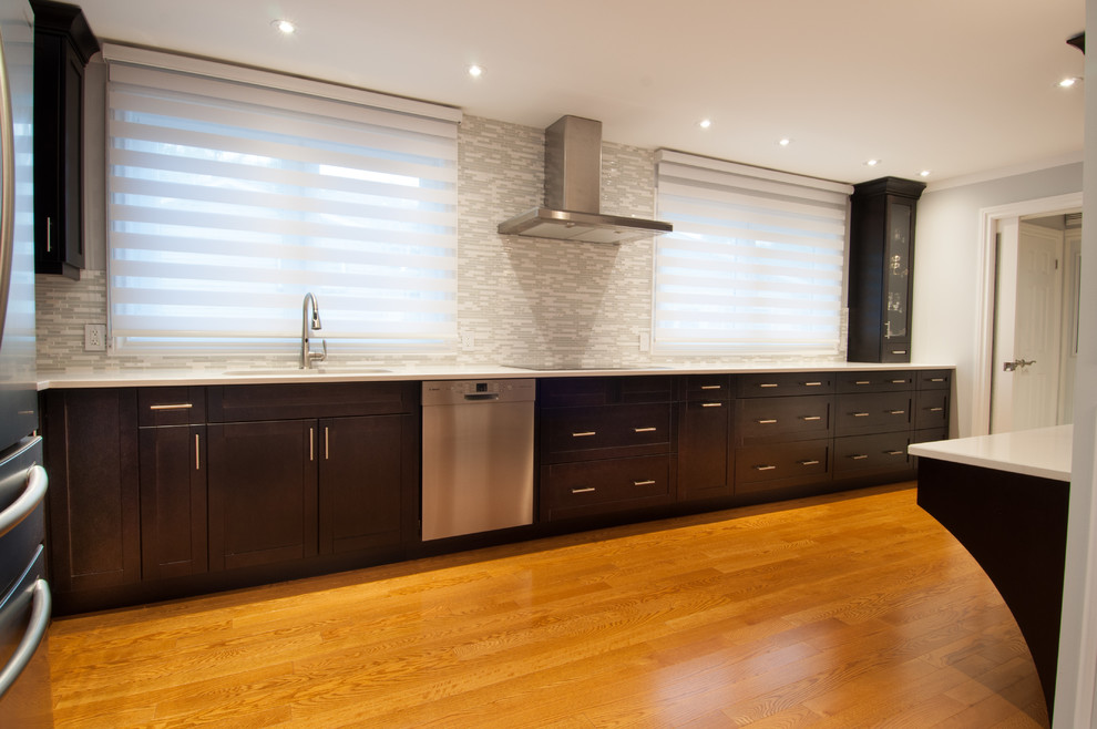 Example of a large transitional galley light wood floor enclosed kitchen design in Toronto with a single-bowl sink, shaker cabinets, dark wood cabinets, quartzite countertops, beige backsplash, stone tile backsplash, stainless steel appliances and an island