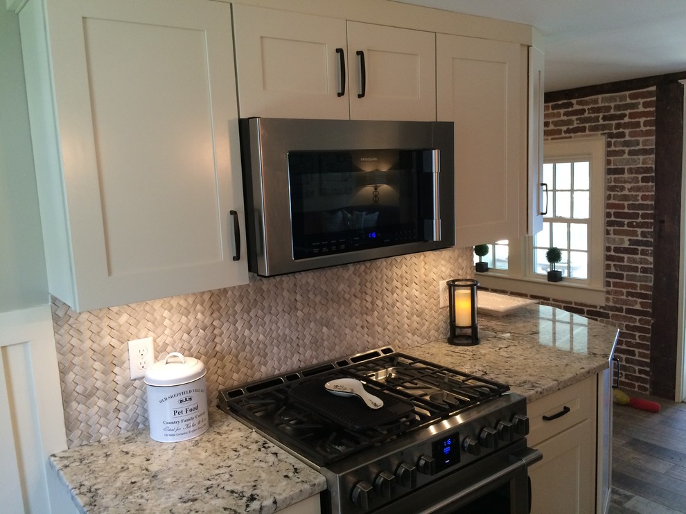 Inspiration for a small transitional medium tone wood floor kitchen remodel in Boston with shaker cabinets, white cabinets, granite countertops, beige backsplash, stone tile backsplash, stainless steel appliances and no island