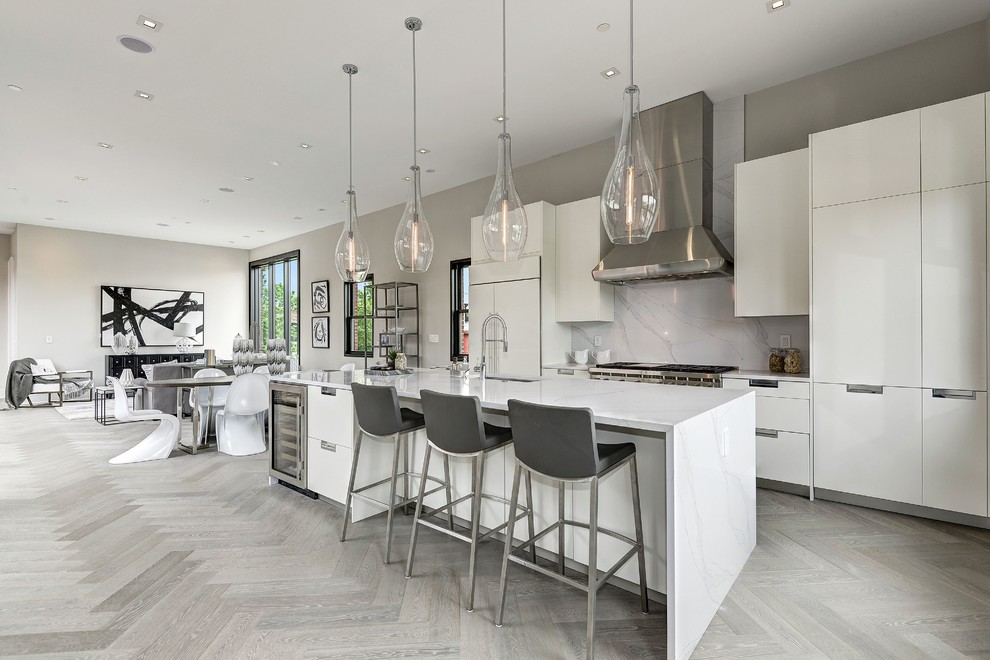 Photo of a large contemporary open plan kitchen in DC Metro with an undermount sink, flat-panel cabinets, white cabinets, quartz benchtops, white splashback, stainless steel appliances, light hardwood floors, with island, marble splashback and beige floor.