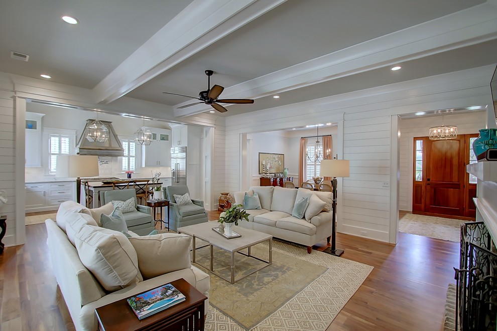 This is an example of a large transitional open concept living room in Charleston with white walls, medium hardwood floors, a standard fireplace, a brick fireplace surround and a wall-mounted tv.