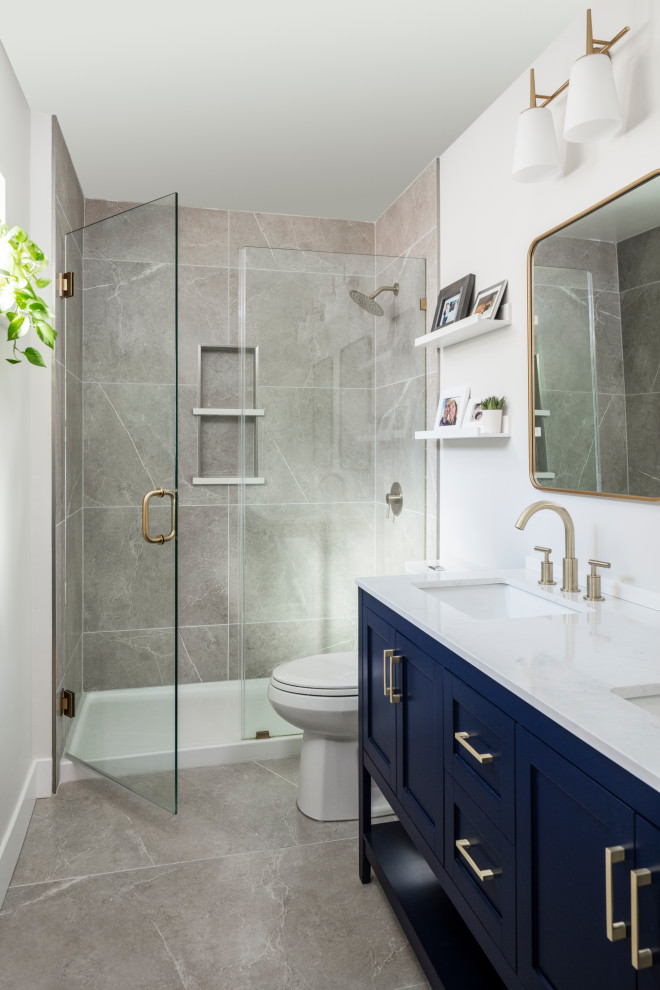 This is an example of a mid-sized transitional master bathroom in Denver with blue cabinets, beige tile, porcelain floors, marble benchtops, grey floor, white benchtops, a niche, a double vanity and a freestanding vanity.