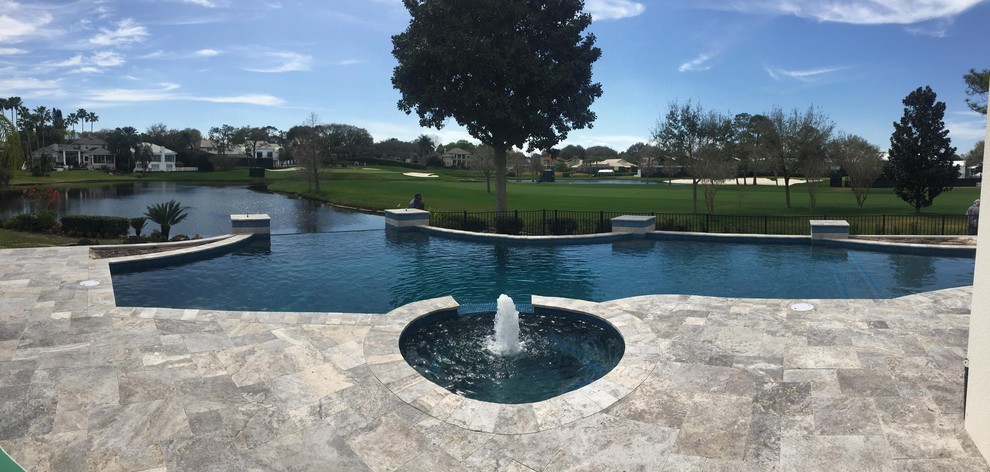 Large transitional backyard tile and custom-shaped infinity hot tub photo in Orlando