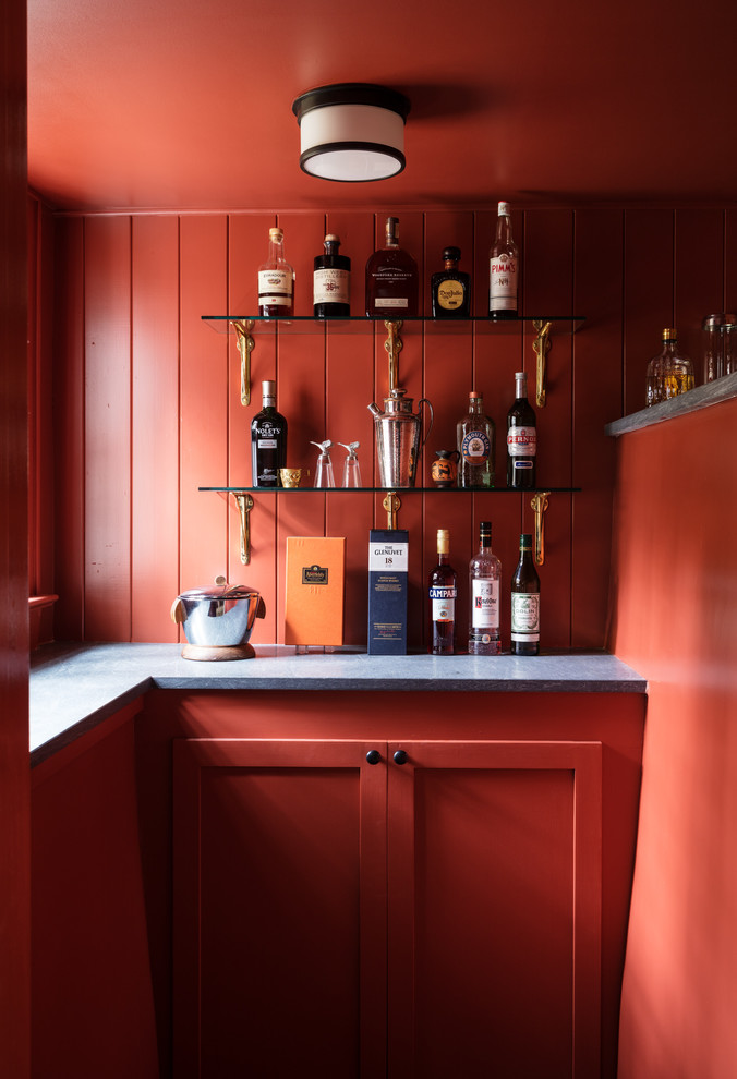Photo of a traditional l-shaped home bar in New York with no sink, shaker cabinets, red cabinets, red splashback, timber splashback and grey benchtop.