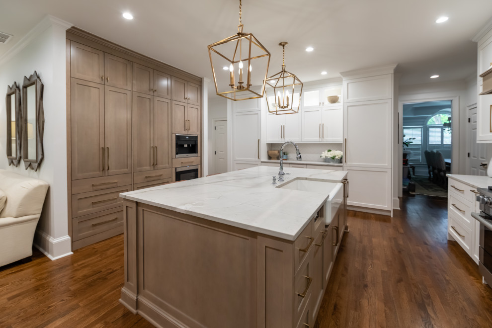 Photo of a large arts and crafts eat-in kitchen in Atlanta with a farmhouse sink, flat-panel cabinets, white cabinets, quartzite benchtops, white splashback, engineered quartz splashback, stainless steel appliances, medium hardwood floors, with island, brown floor and white benchtop.